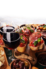 Italian antipasti wine snacks set. Cheese variety, Mediterranean olives, seafood salad, Prosciutto di Parma, tomatoes, anchovy and wine in glasses