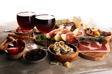 Italian antipasti wine snacks set. Cheese variety, Mediterranean olives, seafood salad, Prosciutto di Parma, tomatoes, anchovy and wine in glasses