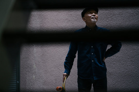 スケートボードを持ち、ハンチング帽を被ったシニア男性のポートレート