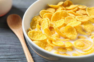 Tasty crispy corn flakes with milk in bowl, closeup