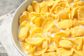 Tasty crispy corn flakes with milk in bowl, closeup