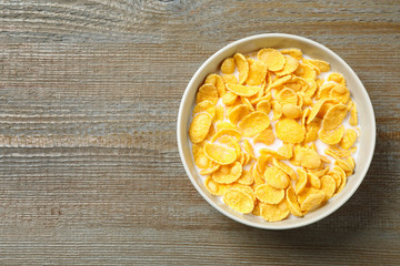Tasty crispy corn flakes with milk on wooden  table, top view. Space for text