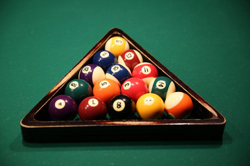 Sports game of billiards on a green cloth. Multi-colored billiard balls in a wooden triangle with numbers on a pool table. Active leisure and entertainment. Billiards. Billiard balls close up. Wood