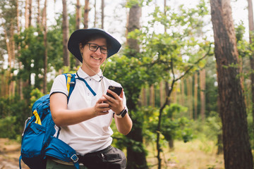 Girl tourist use smartphone on hike, looks maps and navigation. Woman with backpack using smart...