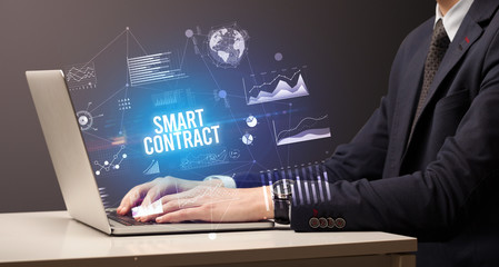 Businessman working on laptop with SMART CONTRACT inscription, new business concept