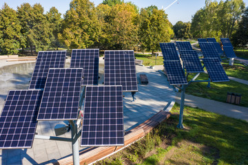 Aerial view of a solar panel Photovoltaic modules installed in a city park with a fountain.  Photovoltaic solar panels absorb sunlight as an energy source for generating electricity. Warsaw. Poland.