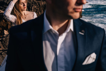  groom in a jacket and shirt in the foreground. bride in white d
