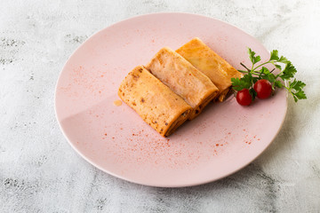 Savory crepe rolls with ground meat filling served with tomatoes. Traditional Russian Shrovetide Maslenitsa festival meal isolated on white marble background. Homemade food. . Hotizontal photo.