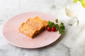 Savory crepe rolls with ground meat filling served with tomatoes. Traditional Russian Shrovetide Maslenitsa festival meal isolated on white marble background. Homemade food. . Hotizontal photo.