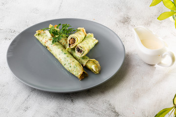 Savory Homemade Mushroom and Spinach green Crepes with Cheese isolated on white marble background. Homemade food. Tasty breakfast. Selective focus. Hotizontal photo.