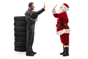 Auto mechanic gesturing high five with a Santa Claus