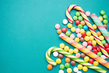 multi-colored caramel on a green background. Lollipops in the form of a cane, jelly beans and caramel sticks.