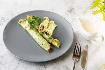 Savory Homemade Mushroom and Spinach green Crepes with Cheese isolated on white marble background. Homemade food. Tasty breakfast. Selective focus. Hotizontal photo.