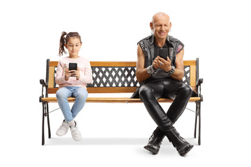 Little girl and a punk using mobile phones and sitting on a bench