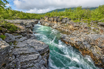 The flow of Abiskojokk river through the rocky canyon in Abisko National park in Northern Sweden.