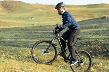 Fototapeta premium Cyclist in pants and fleece jacket on a modern carbon hardtail bike with an air suspension fork rides off-road. 
