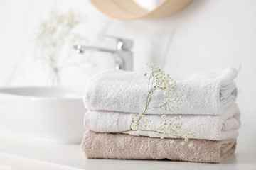 Fototapeta na wymiar Clean towels and flowers on counter in bathroom