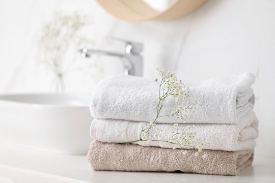 Stacked clean fluffy towels in a bathroom Stock Photo by FabrikaPhoto