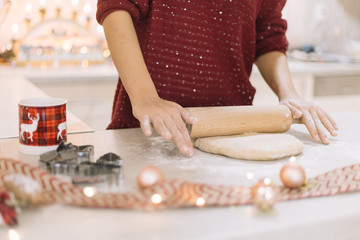 Cropped woman rolling dough on counter with Christmas decoration