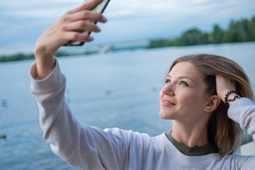 Fototapeta na wymiar Young woman taking selfies on water background