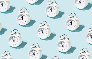 Pattern made of white alarm clocks on blue background. Trendy conceptual photo with open composition. - obrazy, fototapety, plakaty