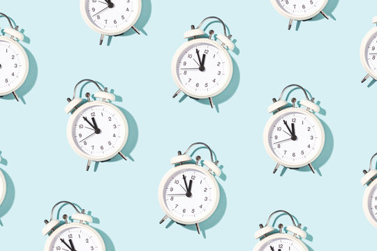 Pattern made of white alarm clocks on blue background. Trendy conceptual photo with open composition.