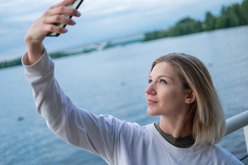 Fototapeta na wymiar Young woman taking selfies on water background