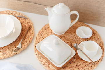 White ceramic tableware, fibre braided round placemat and cutlery set on white background. Scandinavian style.