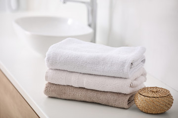 Fototapeta na wymiar Stack of fresh towels on countertop in bathroom