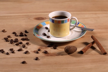 cup of coffee on saucer garnished with cinnamon sticks and nutmeg