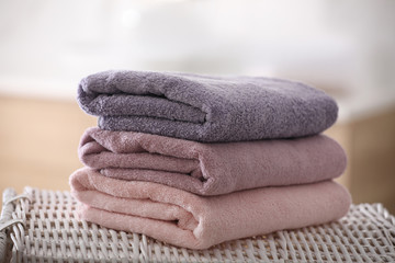 Stack of fresh towels on wicker stand in bathroom