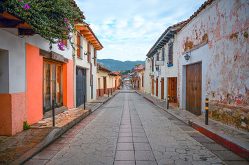 Fototapeta na wymiar Colorful street of a Mexican town San Cristobal De Las Casas in Chiapas, in the background wooded mountains and a cloudy sky