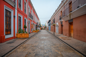 Main street of San Cristobal De Las Casas, colorful Mexican type town, colonial houses and mountains and cloudy sky in the background