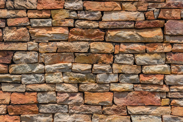 generic background of a non wall of irregular grungy non pointed stones in summer colors in the sun with some shadows on the stones