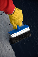 Worker applies bitumen mastic on the foundation