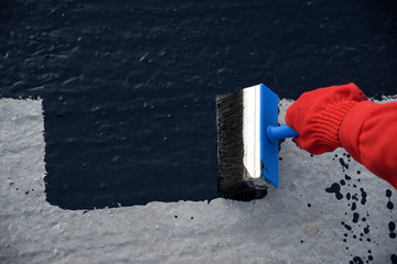 Worker applies bitumen mastic on the foundation