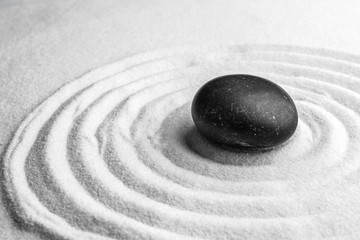 Fototapeta na wymiar Black stone on sand with pattern. Zen, meditation, harmony