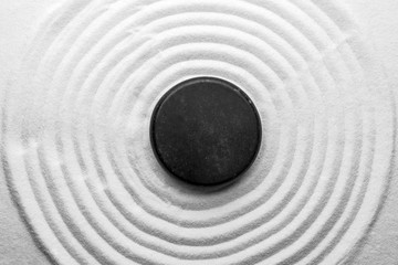 Black stone on sand with pattern, top view. Zen, meditation, harmony - obrazy, fototapety, plakaty