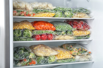 Plastic bags with different frozen vegetables in refrigerator