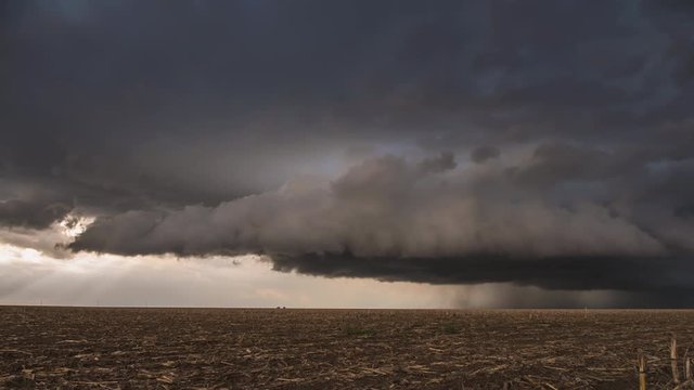 Wall cloud rolling over the landscape in dark dramatic storm during tornado warning.