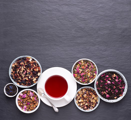 Cup of fruit tea on dark, stone background, top view with copy space