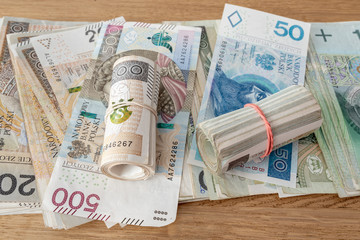 Polish banknotes lay on the table. Polish currency on a wooden background. Various Polish denominations. Polish zloty.