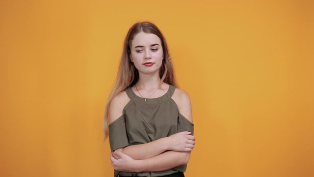 Portrait of confused young woman with closed eyes and covering nose with hand, like crying isolated on orange wall background in studio. People sincere emotions, lifestyle concept.