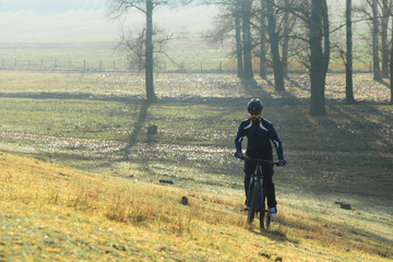 Cyclist in pants and fleece jacket on a modern carbon hardtail bike with an air suspension fork. The guy on the top of the hill rides a bike.