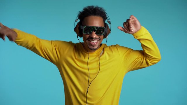 African american man with headphones dancing with hands isolated on blue background. Party, music, lifestyle, radio and disco concept.