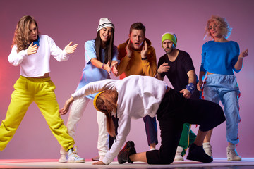 Attractive sportive woman in sportswear, performing on concert stage, surrounded by young dancers, exercising hip hop movie on floor of dance studio
