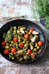 Selective focus. Frying pan with baked Brussels sprouts with cherry tomatoes, olives and thyme. Vegan food. Healthly food.