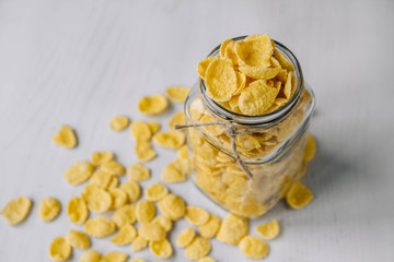 Corn flakes in a glass jar on white wooden surface. Top view. Place for your text