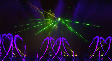 Colorful water fountains. Beautiful laser and fountains show. Large multi colored decorative dancing water jet led light fountain show at night. Dark background.