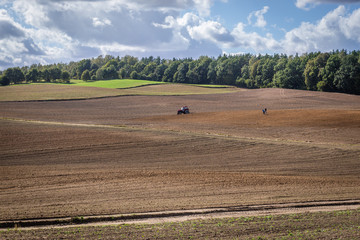 Obraz premium Tractor on field on the border of Ostroda and Ilawa counties, Masuria region in Poland